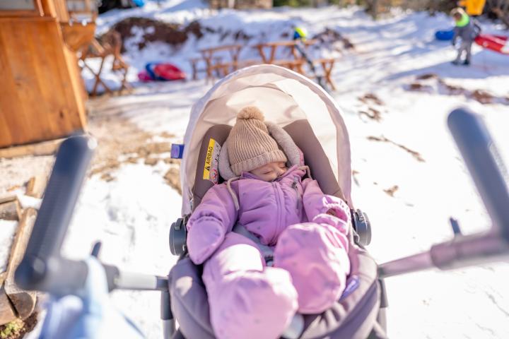 Niña durmiendo en cochecito de bebé al aire libre en un día de invierno