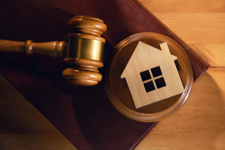 Mazo de justicia junto a una figura de una casa.