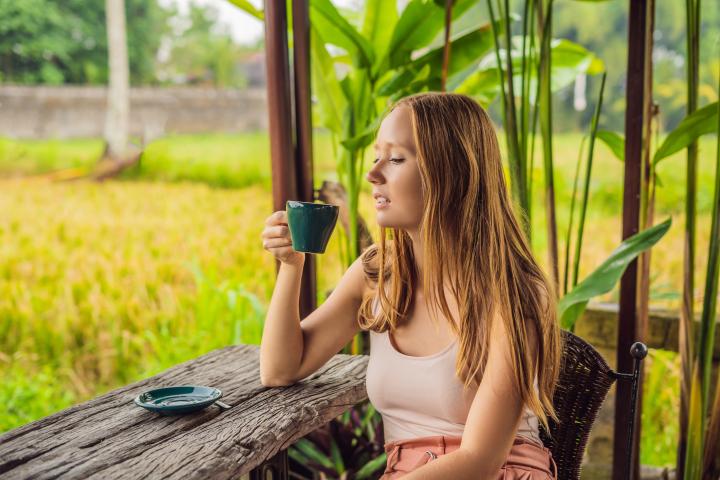 Mujer con una taza de café en la terraza de la cafetería cerca de las terrazas de arroz en Bali, Indonesia.