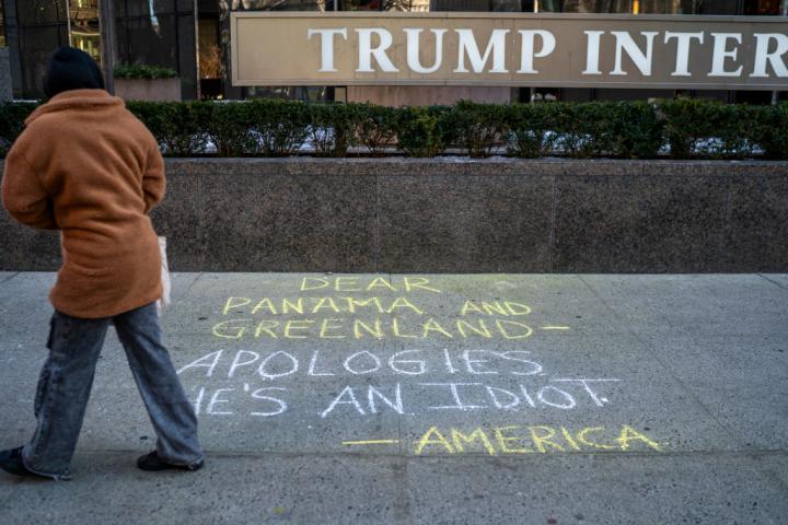 Un peatón pasa ante el Trump Hotel de Nueva York, donde alguien ha hecho una pintada pidiendo disculpas a Groenlandia y Panamá. "Es un idiota", se lee, en referencia al presidente de EEUU.