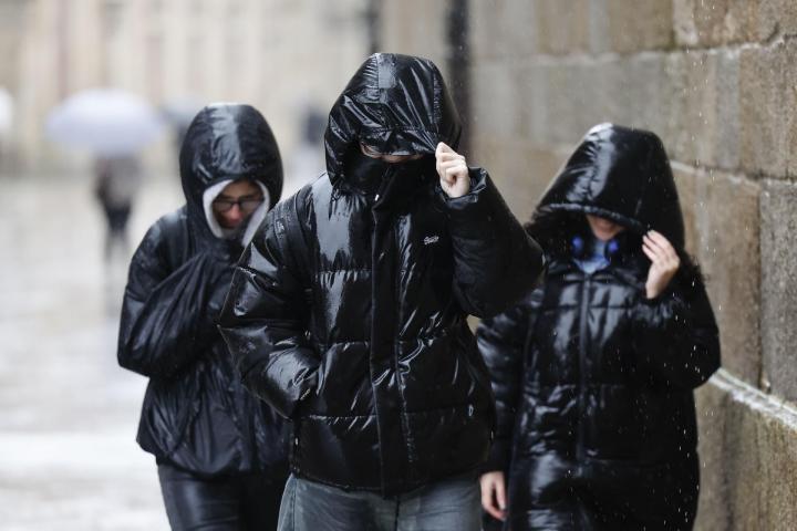 Varias chicas caminan bajo la lluvia en Santiago de Compostela, el 21 de enero de 2026, en los primeros coletazos del temporal Ingrid.