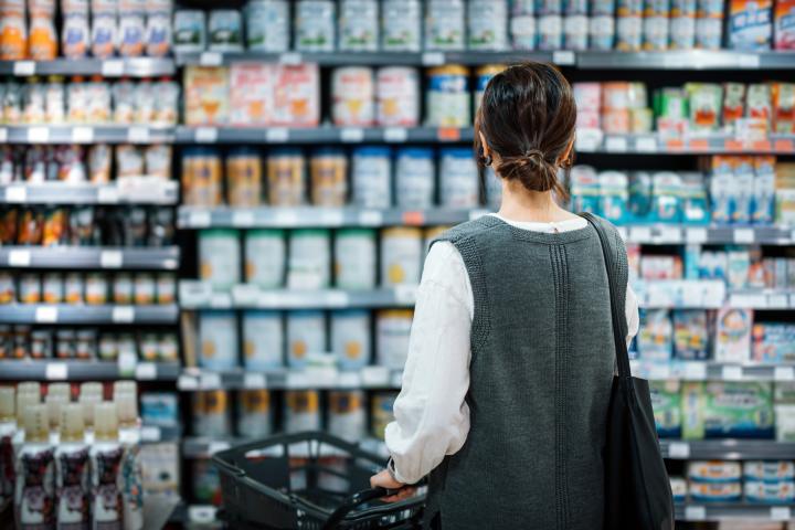 Una mujer decide qué leche en polvo comprar en el supermercado.