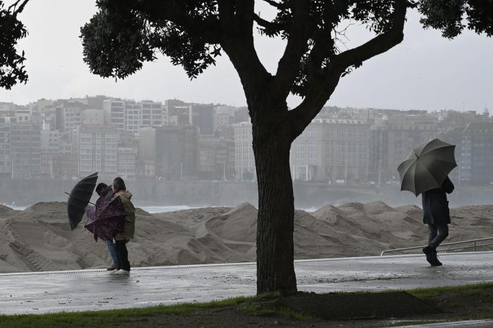 Unos ciudadanos tratan de protegerse del temporal en A Coruña, el 21 de enero de 2026.