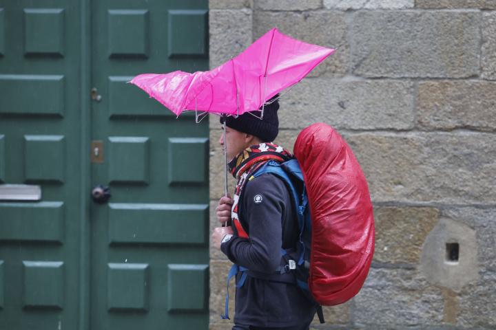 Una persona se protege de la fuerte lluvia en la plaza del Obradoiro, en Santiago de Compostela.