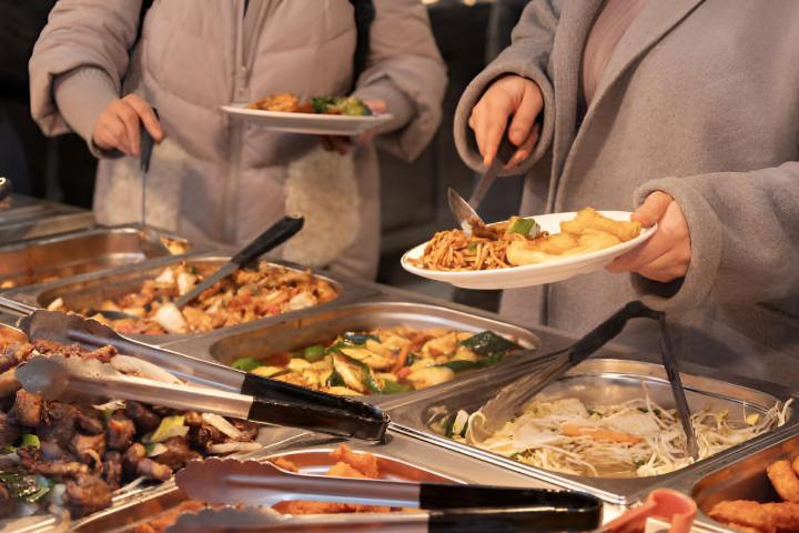 Dos personas llenando sus platos en un buffet libres