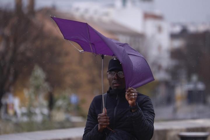 Un hombre intenta protegerse de la lluvia y el viento en Córdoba.