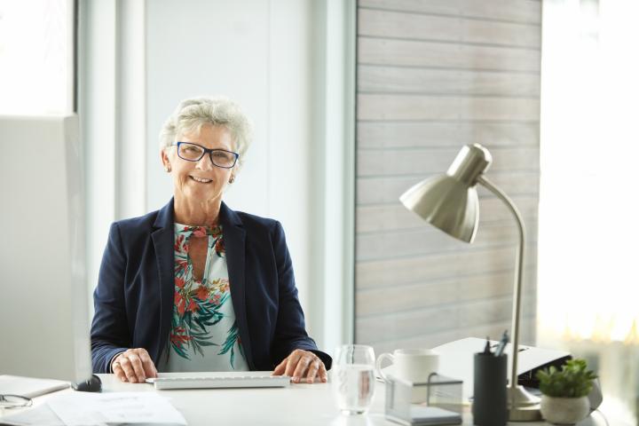 Fotografía de una empresaria senior trabajando en su escritorio en una oficina moderna.