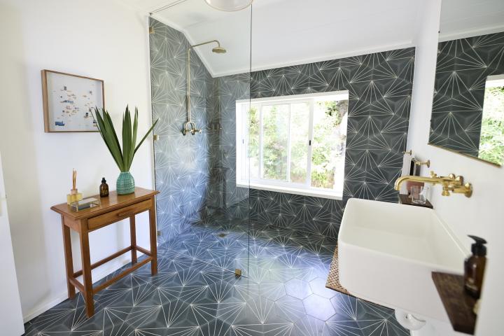 Interior de baño con cabina de ducha de cristal y suelo estampado.