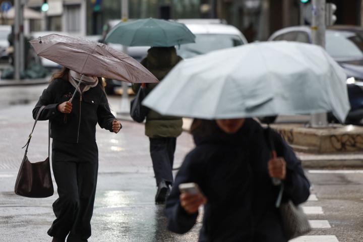 Varias personas se protegen de la lluvia en Madrid, en una imagen de archivo.