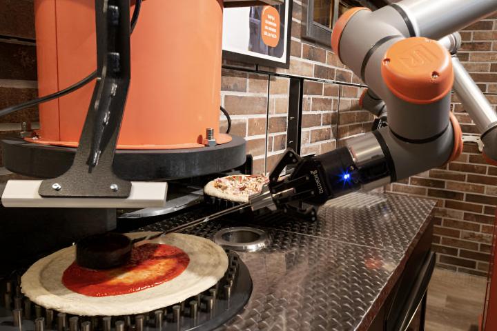 Un robot preparando una pizza en la primera pizzería robótica de París
