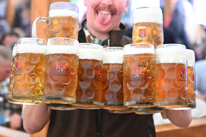 Camarero sostiene varias jarras de cerveza durante una celebración popular en Alemania