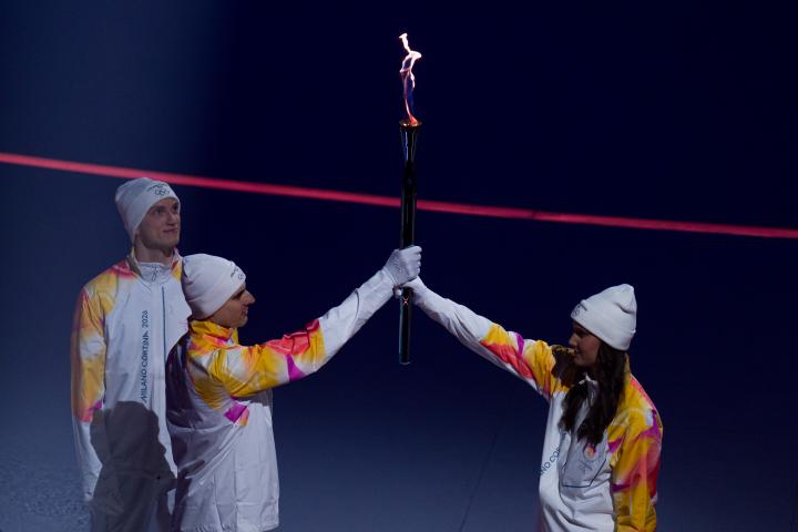 Los atletas del equipo de Italia entregan la llama olímpica al siguiente grupo de portadores de la antorcha durante la ceremonia de apertura de los Juegos Olímpicos de Invierno