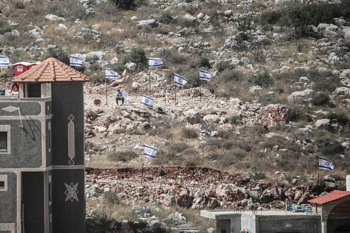 Colonos judíos izan banderas israelíes en viviendas palestinas en la aldea de Bruqin, en Cisjordania, el 19 de mayo de 2025.