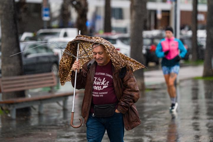 Un hombre en Barcelona, con el paraguas roto.