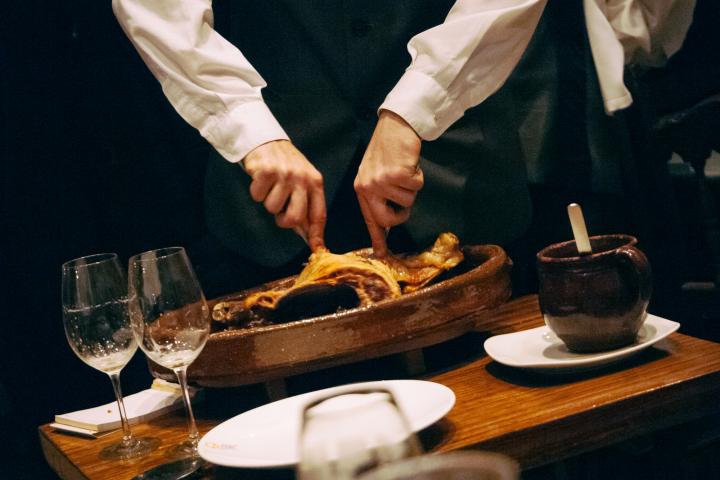 Hombre sirviendo cochinillo en un restaurante de Castilla y León.