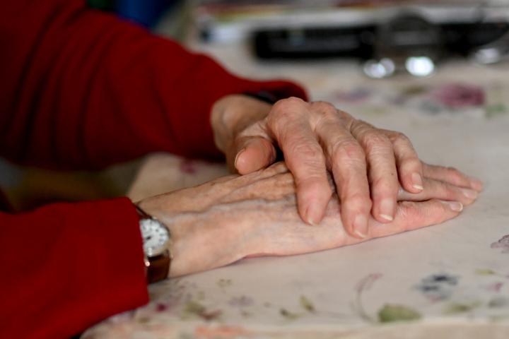 Las manos de una señora mayor apoyadas sobre una mesa