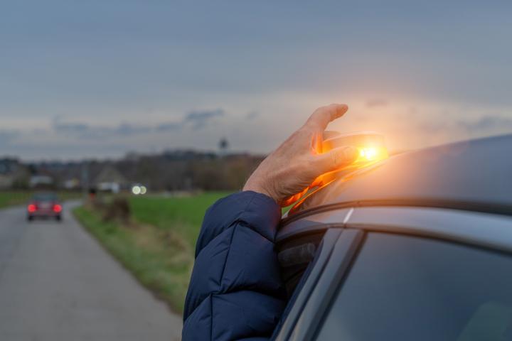 Un conductor colocando una baliza V-16 en su coche