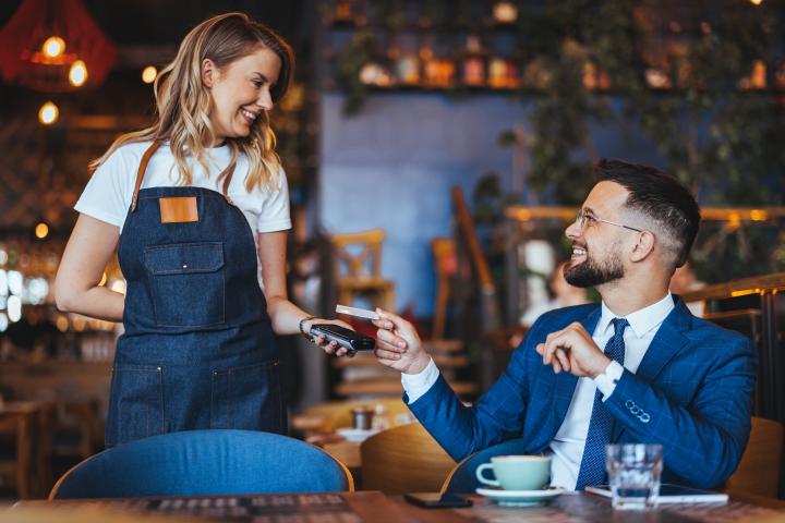 Un cliente vestido con traje, pagando en un restaurante.