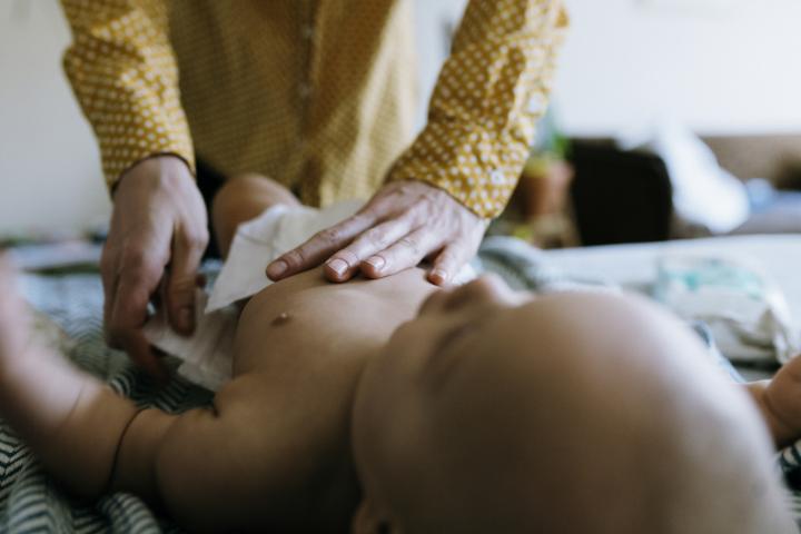 Una madre le pone un pañal a su bebé