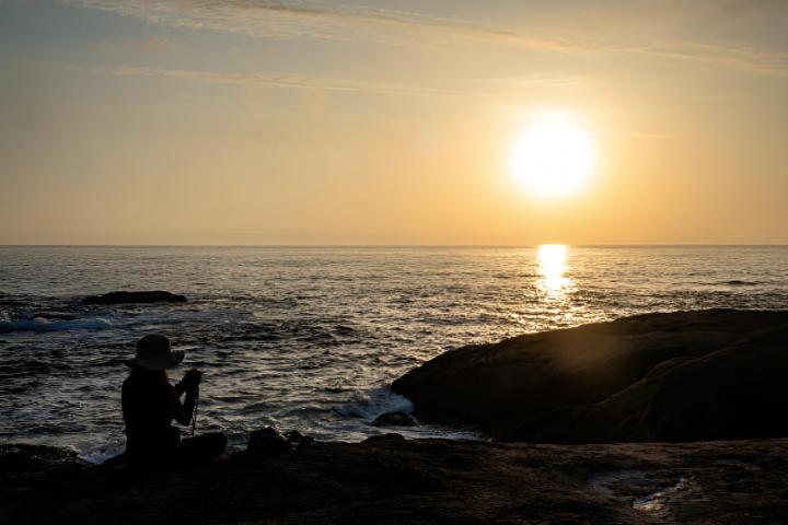 Una mujer haciendo fotografías del atardecer en una de las paradas de la ruta de peregrinación a Muxía
