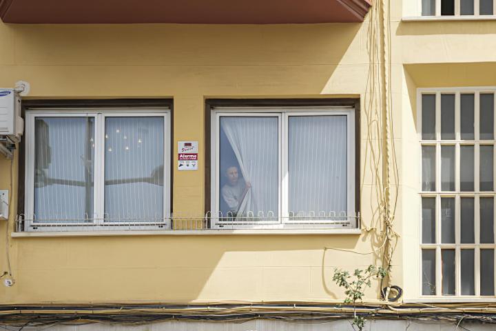 Una mujer mirando por la ventana de una casa