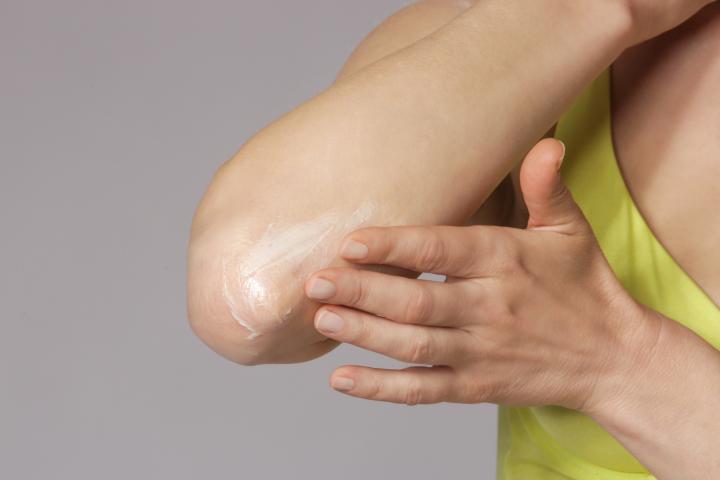 Mujer se aplica manteca de karité en el codo seco.