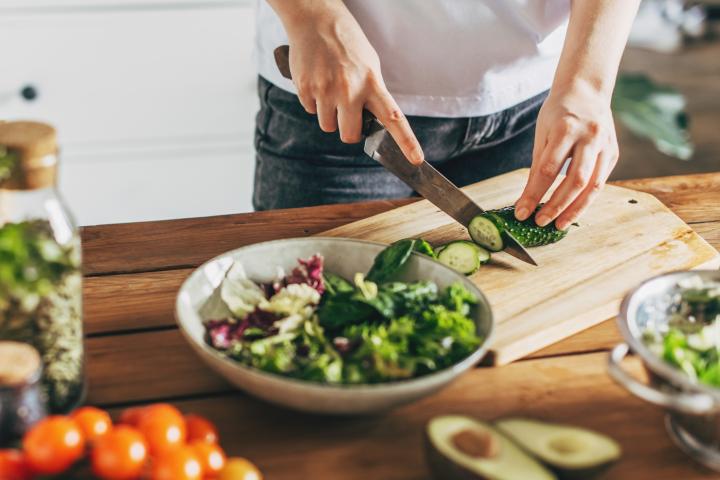 Una mujer cortando verduras en la cocina. Imagen de archivo