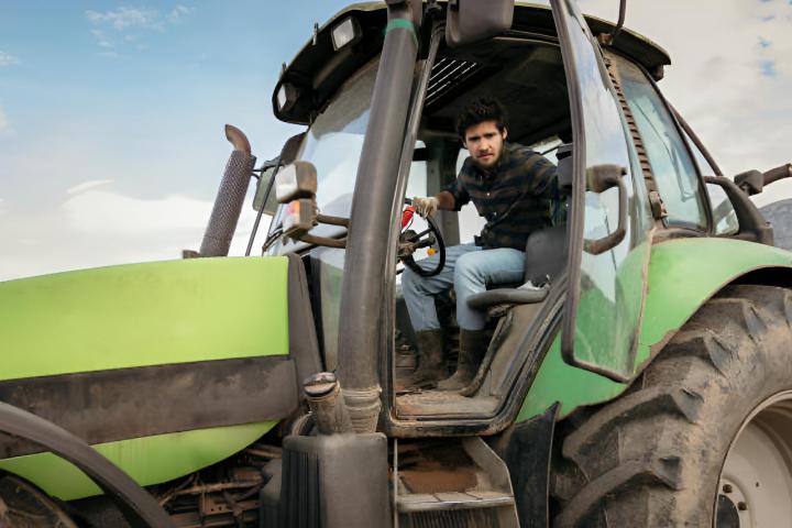 Un agricultor joven que conduce el tractor en el campo