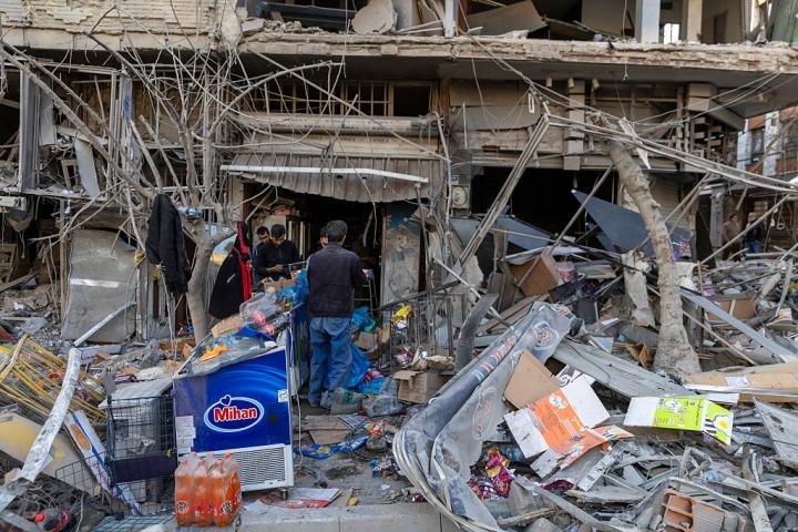 Ciudadanos de Teherán, la capital de Irán, revisan los daños causados en una tienda y una vivienda por los ataques aéreos de EEUU e Israel, 2 de marzo de 2026.