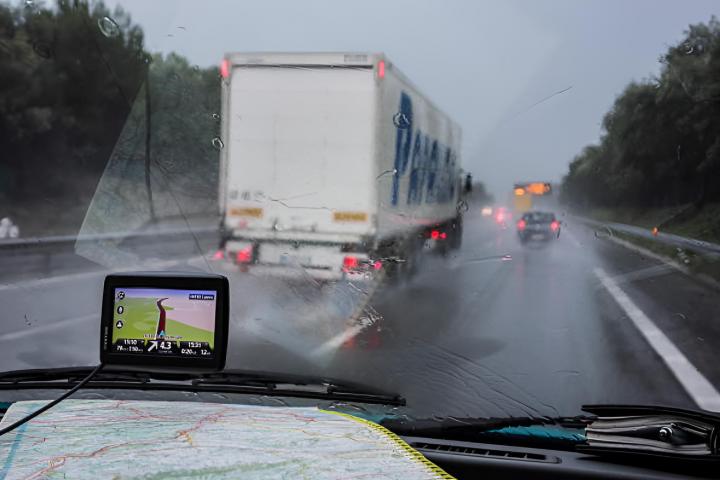 Un camión en la autopista durante una fuerte lluvia siguiendo el GPS y un mapa de carreteras