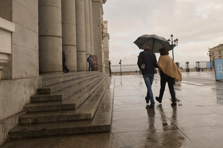 Imagen de archivo de dos personas caminando con un paraguas en Madrid.