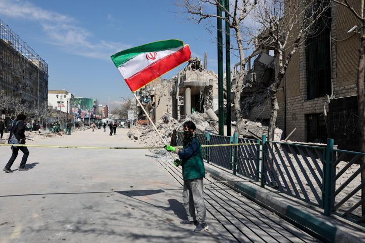 Un niño sostiene una bandera iraní delante de una comisaría atacada por Israel y EEUU, el 4 de marzo de 2026, en Teherán (Irán).