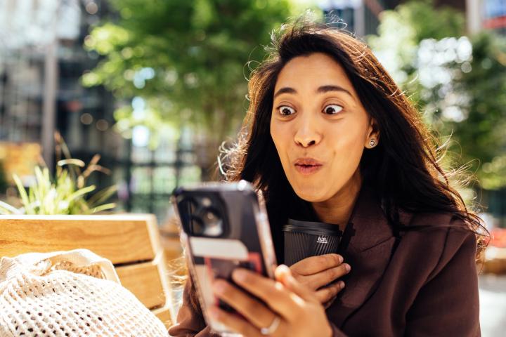 Una mujer se muestra feliz y sorprendida con un mensaje.