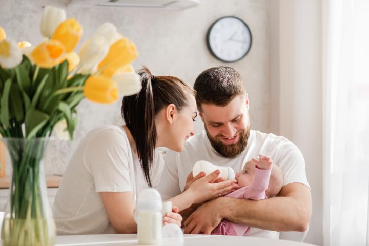 Unos padres dan el biberón a su bebé.