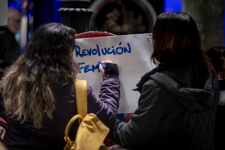 Una joven escribiendo en un cartel, en Madrid, "Revolución feminista".
