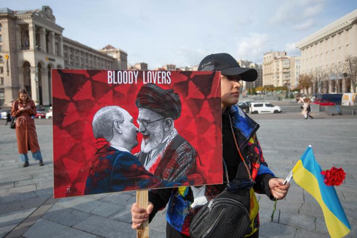 Una mujer sostiene una pancarta con la imagen del presidente ruso, Vladímir Putin, y del líder supremo iraní, Alí ​​Jamenei, en una protesta por el uso de drones iraníes, el 28 de octubre de 2022.