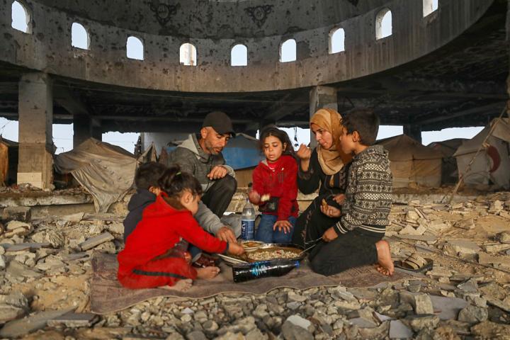 Miembros de la familia palestina Dallul, desplazada del barrio de Zayton, preparan una cena iftar con provisiones limitadas para sus hijos entre los restos de una mezquita atacada por Israel, el 7 de marzo de 2026.