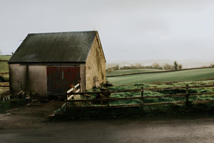 Una escena rural que muestra un antiguo granero en mitad del campo