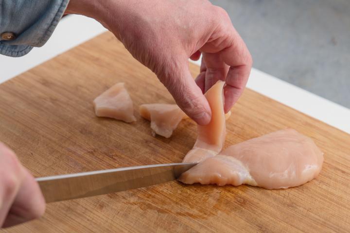 Una persona, cortando un filete de pollo.