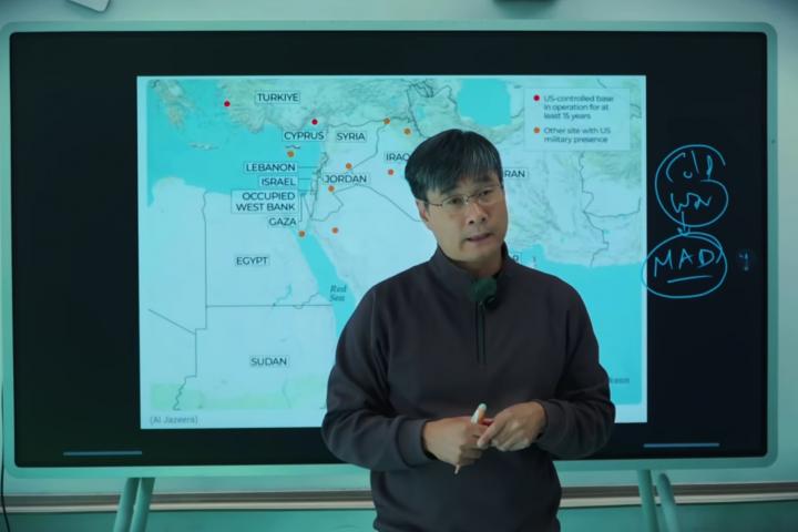 Una imagen del creador de contenido Xueqin Jiang, frente a una pantalla en la que se ve un mapa de Oriente Medio.