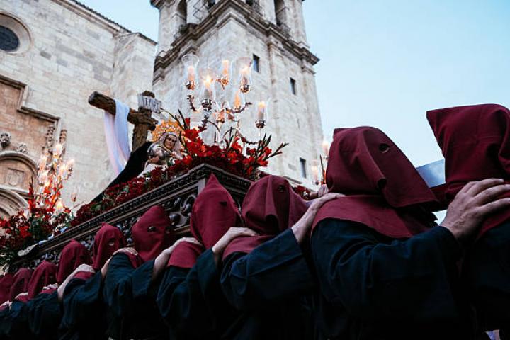 Alcala de Henares, Spain - April 14, 2014: A group of cofrades wearing a mask hold a statue of Christ and the Virgin Mary during a Holy Week procession.