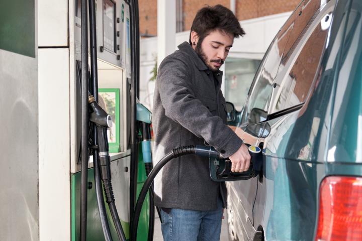 Un hombre joven repostando su coche