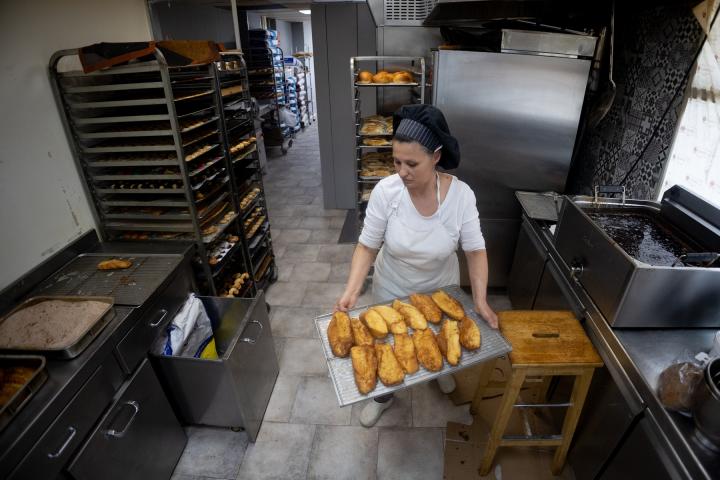 Una pastelera trabaja en un obrador elaborando varias torrijas en Madrid.