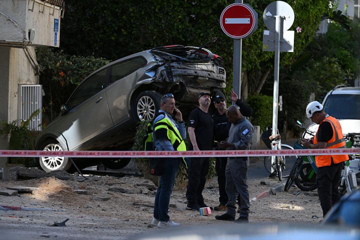 Varios israelíes revisan una calle de Tel Aviv tras el impacto de un proyectil iraní, el 8 de marzo de 2026. El impacto dejó tres heridos.