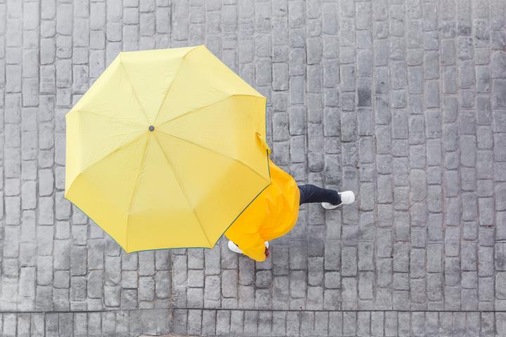 Una persona se protege de la lluvia con un paraguas amarillo