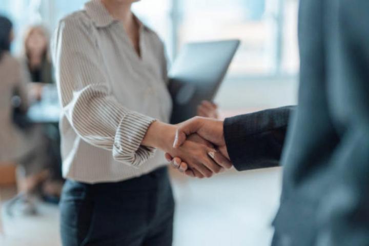 Primer plano de dos empresarios de pie en una oficina dándose la mano