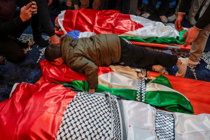 El pequeño Mustafá, sobreviviente del ataque, abraza los cuerpos de sus padres y dos hermanos, atacados por Israel, durante su funeral en Tammoun (Cisjordania), el 15 de marzo de 2026.