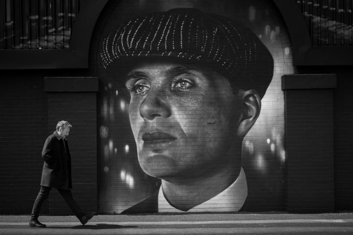 Steven Knight, guionista de Peaky Blinders, junto a un mural de Tommy Shelby, el protagonista.