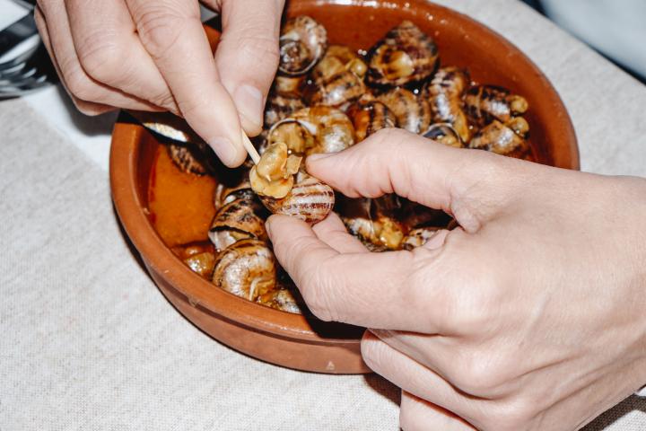Una persona, comiendo un plato de caracoles.