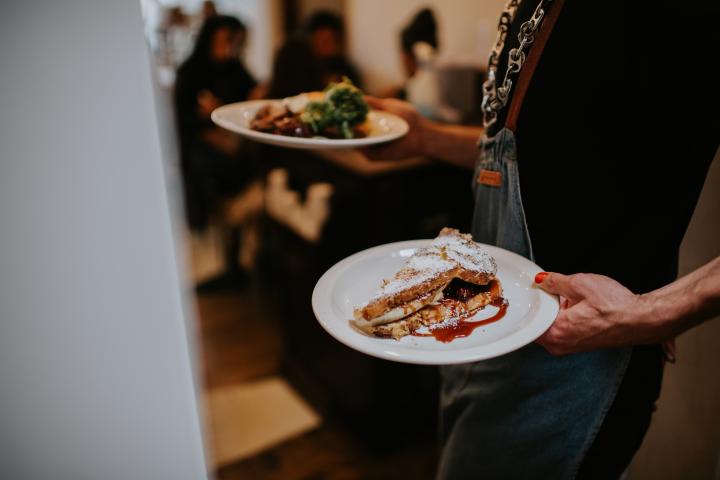 Una camarera, llevando varios platos a la mesa en un restaurante.